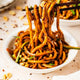 A bowl of thick noodles with visually appealing sauce on a dining table