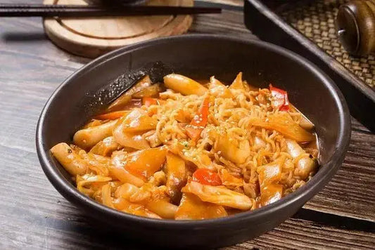 A bowl of vegan tteokbokki on a wooden table