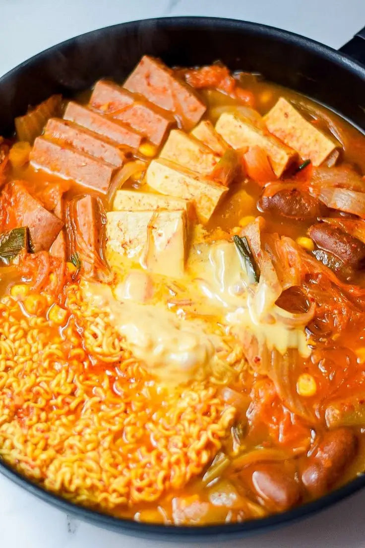 Hot pot with various ingredients in a black pot on a white background